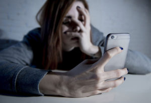 woman looking at her phone wonders how to help an addict